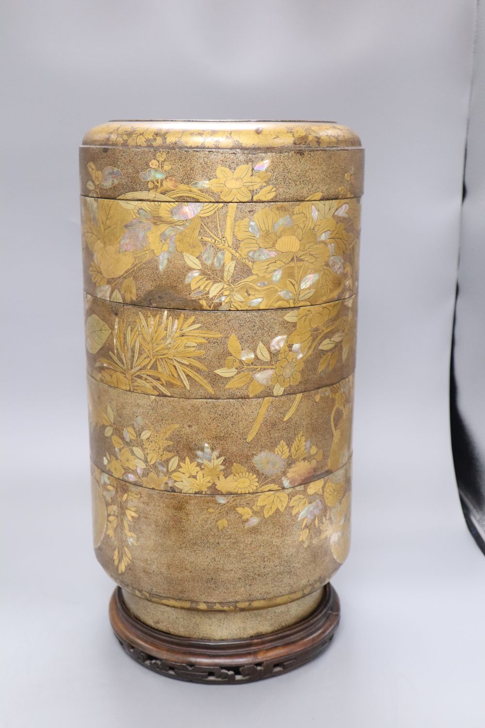 A 19th century Japanese sectional stack of mother of pearl and lacquered boxes, on hardwood stand, overall height 46cm